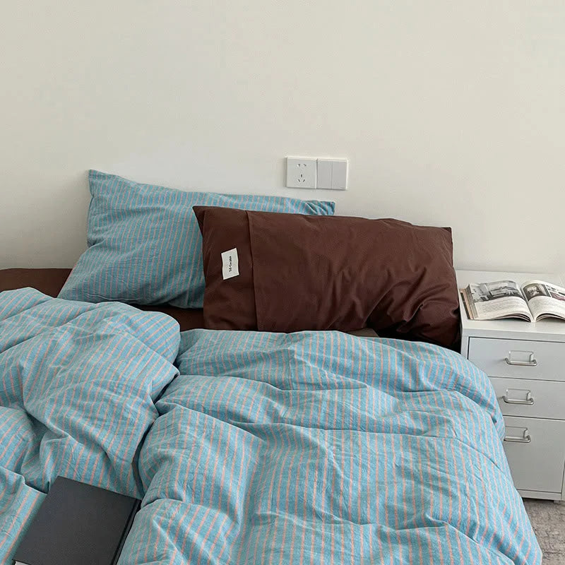 Blue & Brown Striped Washed Cotton Bedding Set on a bed, paired with a solid dark brown pillowcase - RoomDen.