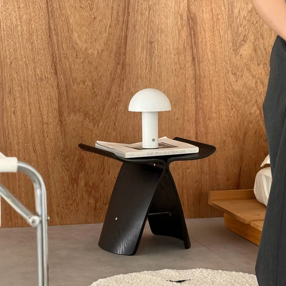 Lifestyle scene of the white mushroom lamp on a designer side table against a warm wood wall - RoomDen.