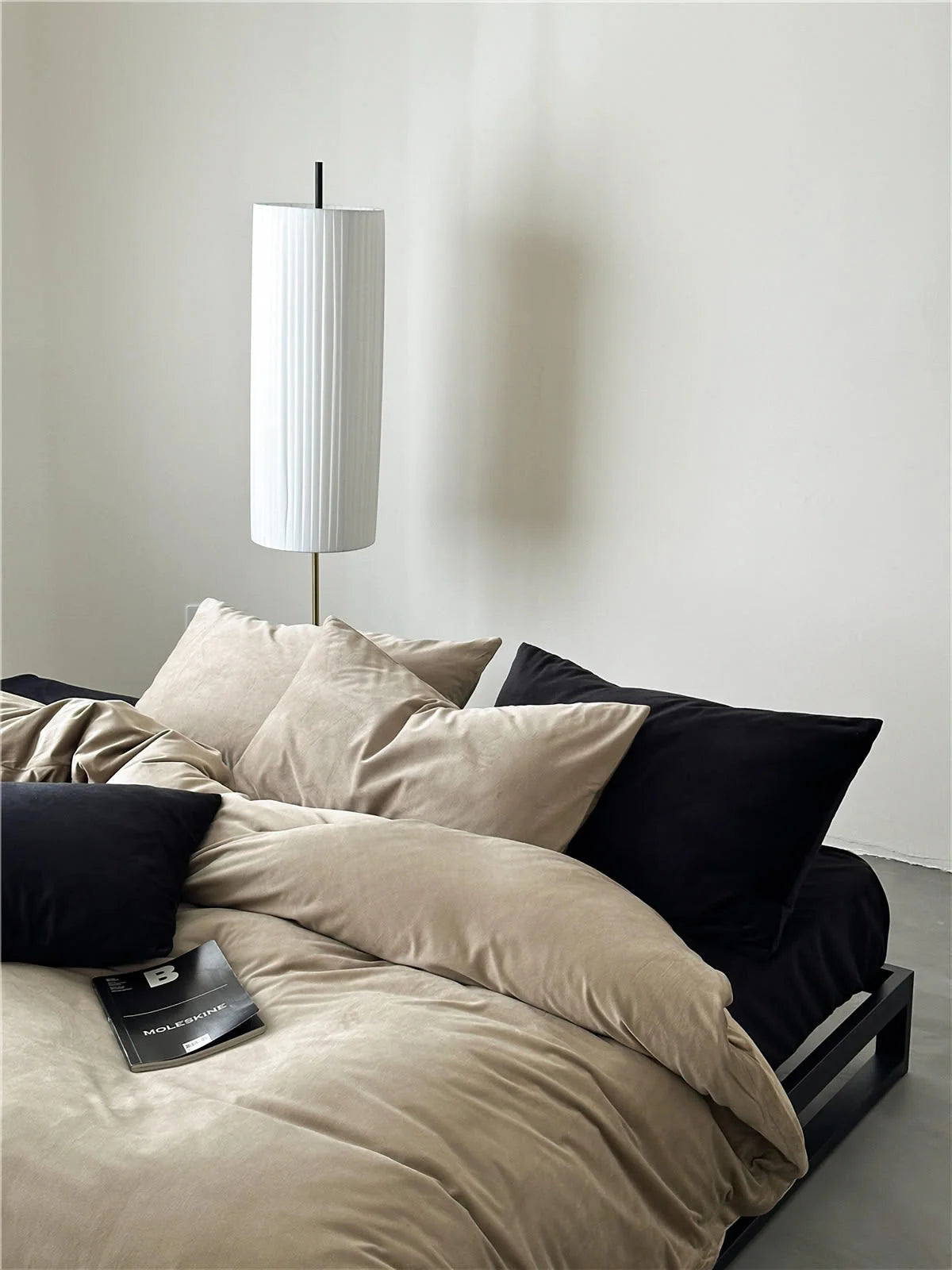 A mix of Warm Beige and black velvet pillows creating a sophisticated and modern bedding arrangement. - RoomDen