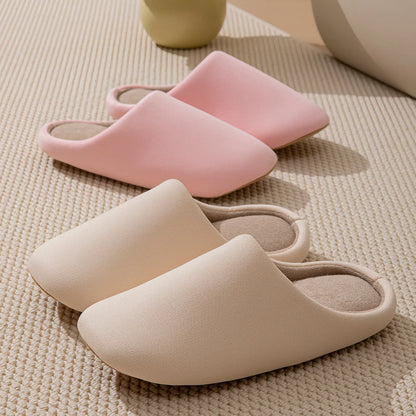 Pink and beige solid color slippers arranged on textured rug - RoomDen