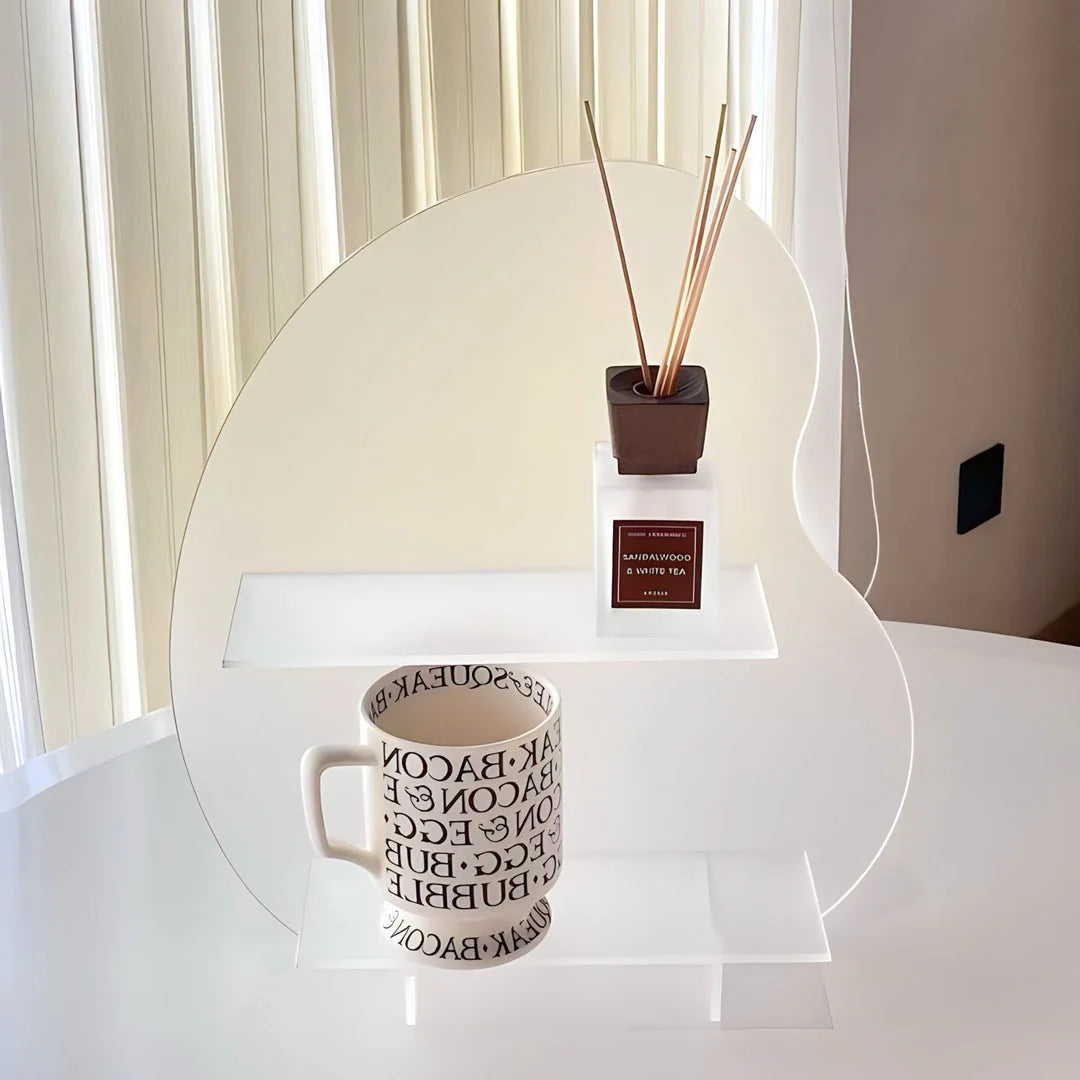 A frosted white wavy acrylic display shelf holding a mug and a diffuser in a brightly lit room. - RoomDen
