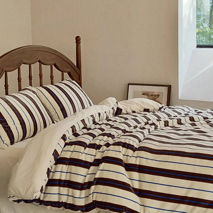 The cream and brown striped velvet bedding set shown in a well-lit room with a wooden bed frame - RoomDen.