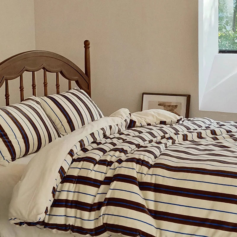 The cream and brown striped velvet bedding set shown in a well-lit room with a wooden bed frame - RoomDen.