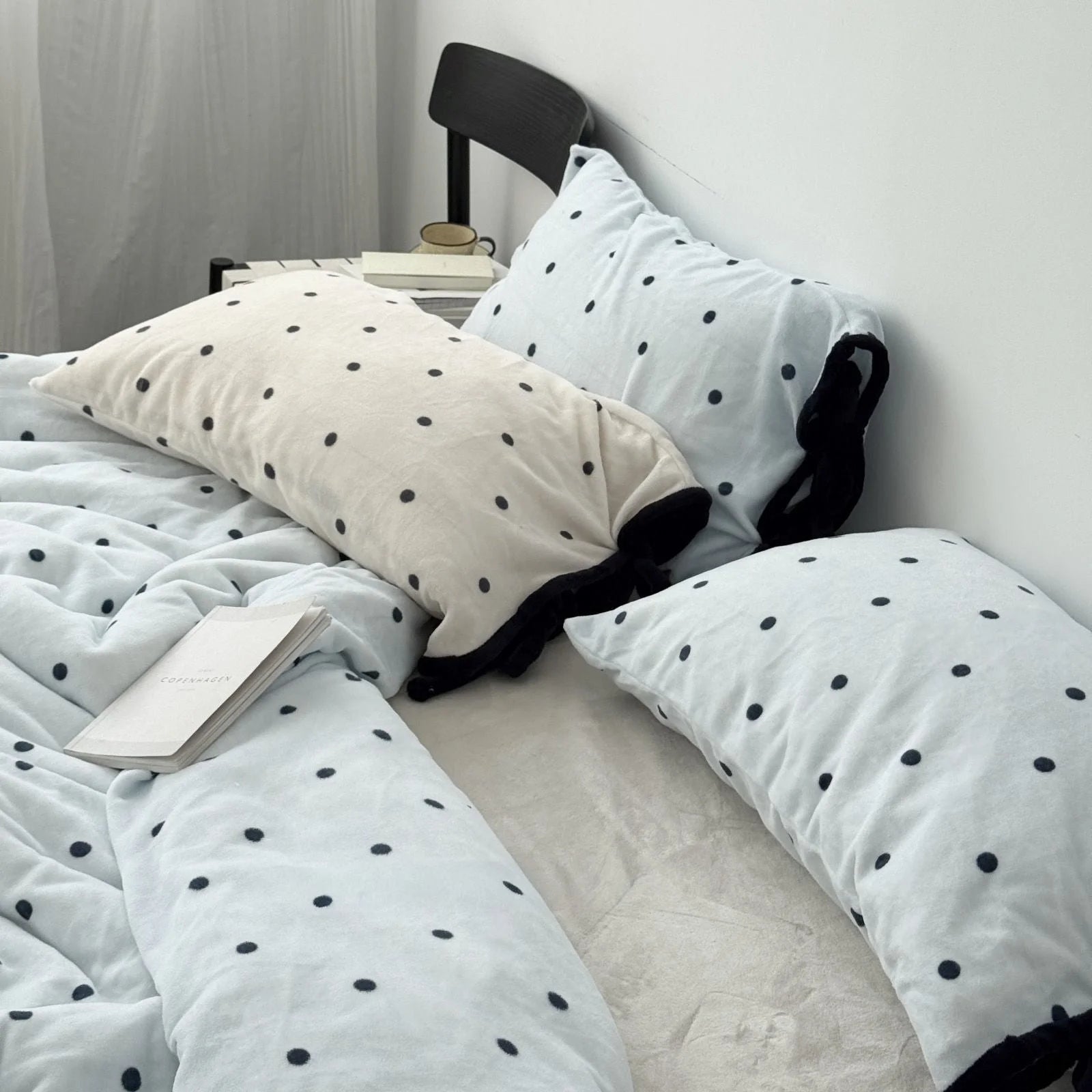 Both Light Blue and Creamy White Polka Dot Flannel Fleece pillows shown together on a bed.