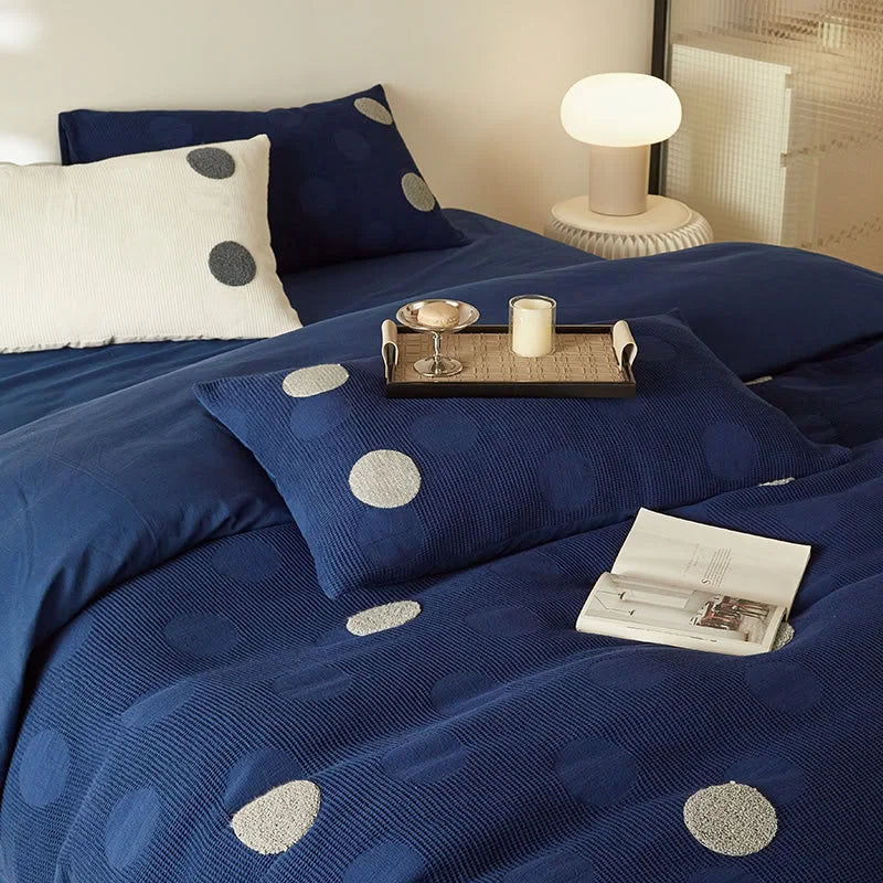 Lifestyle scene with the Navy Polka Dot bedding, a tray with a candle, and a book, creating a Hygge atmosphere. - RoomDen