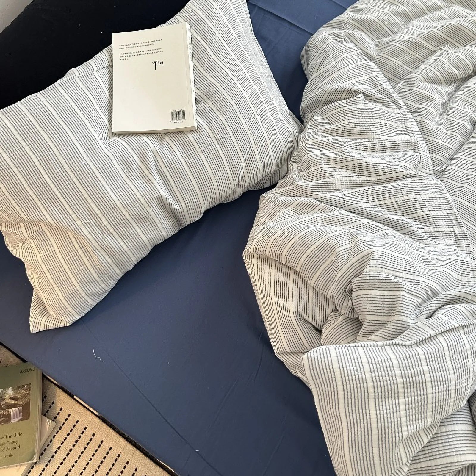 Top-down view of the grey pinstripe washed cotton bedding set with a book resting on the pillow.