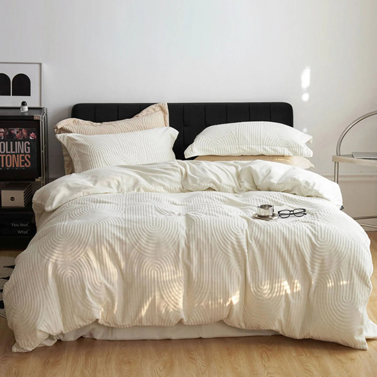 Wide shot of the cream white flannel fleece bedding set styled with a modern black nightstand and art. - RoomDen