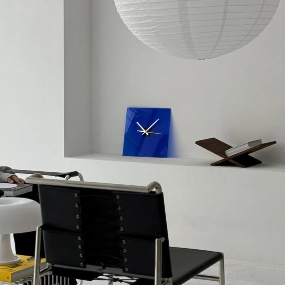 Cobalt Blue acrylic table clock on a white shelf next to a book stand in a modern living room. - RoomDen