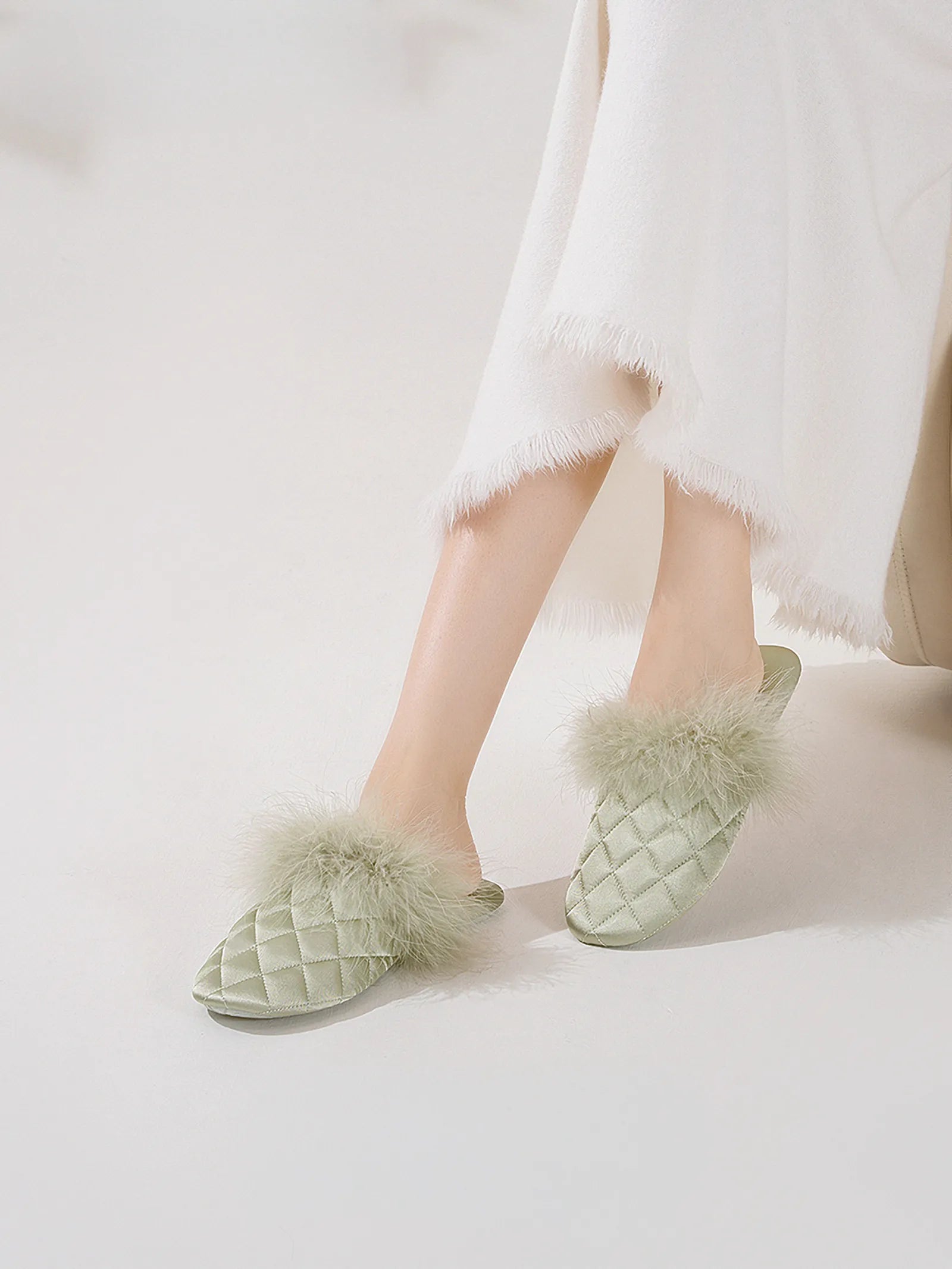 Close up of green satin slides showing plush faux fur detail and legs