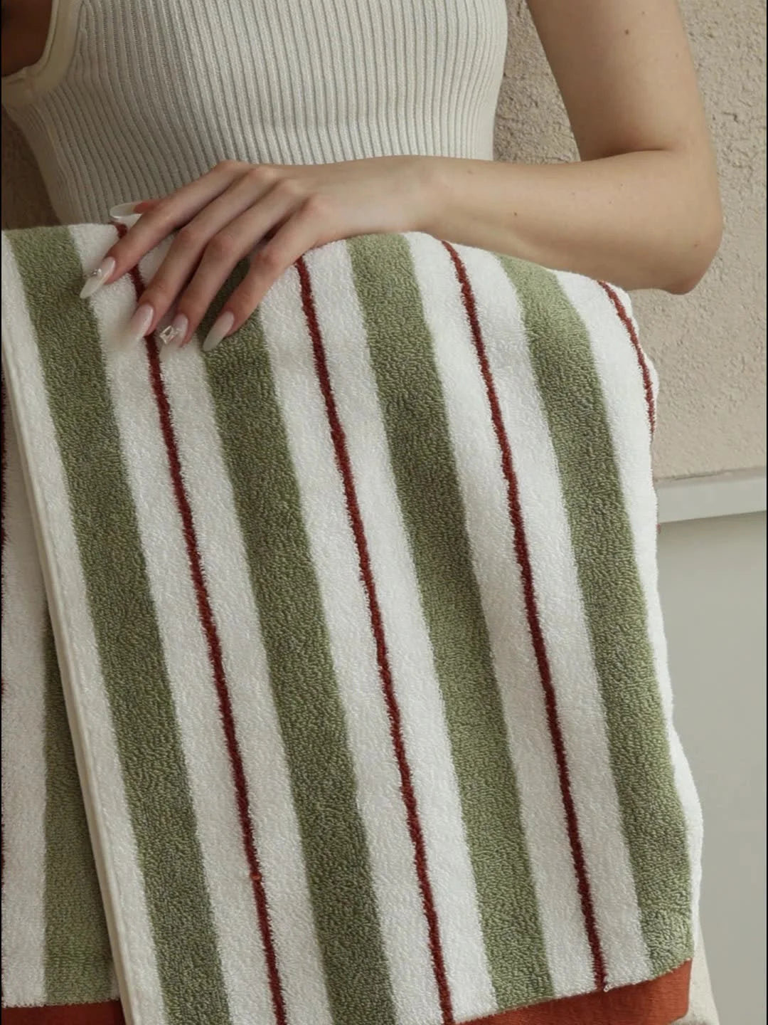Close-up detail of the soft terry cloth texture on the green and white striped cotton towel - RoomDen