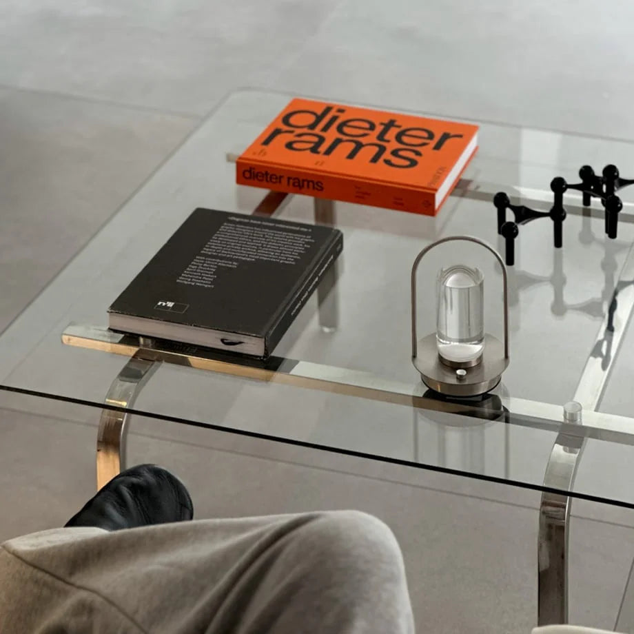Top-down view of the portable metal accent lamp on a glass table next to design books. - RoomDen