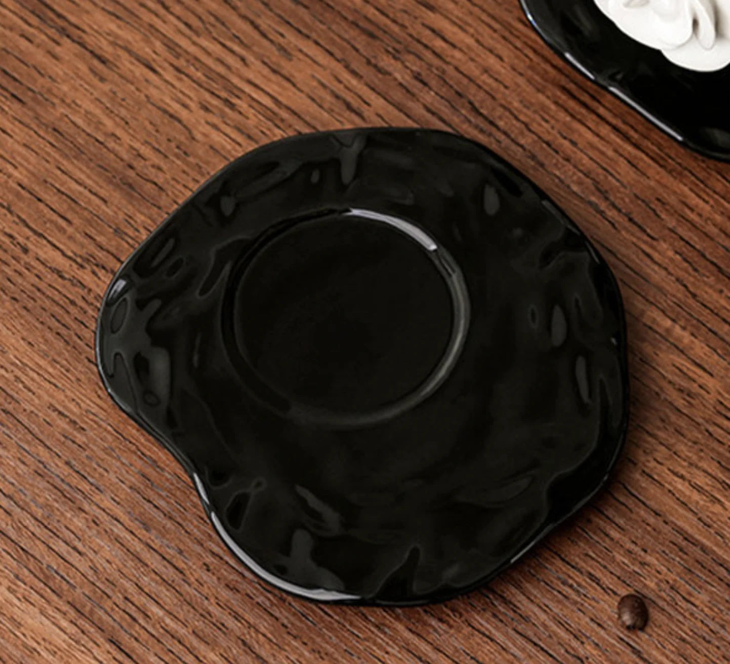 Detailed shot of the wavy, textured black ceramic saucer - RoomDen