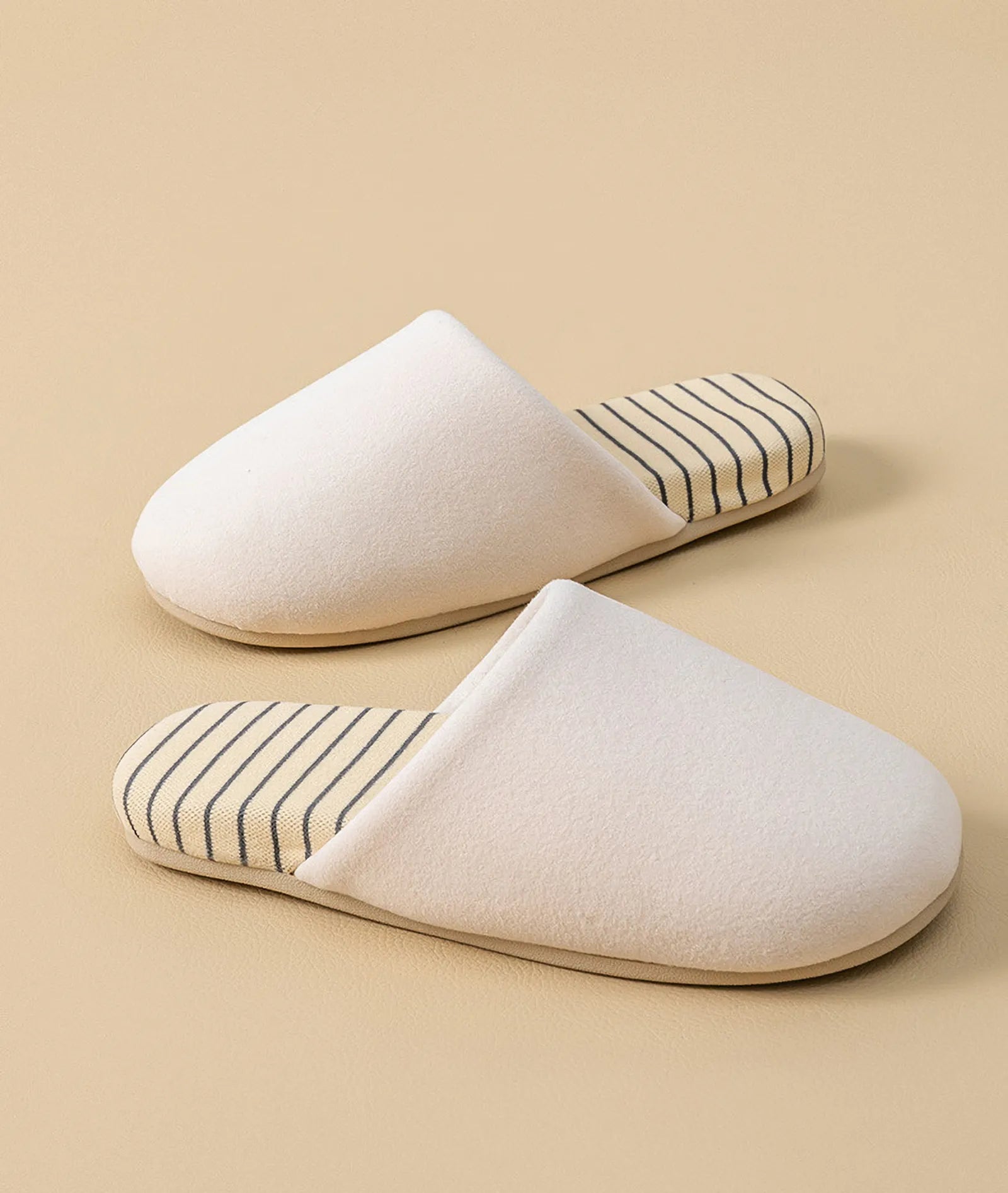 Pair of beige cotton house slippers positioned side by side showing striped interior