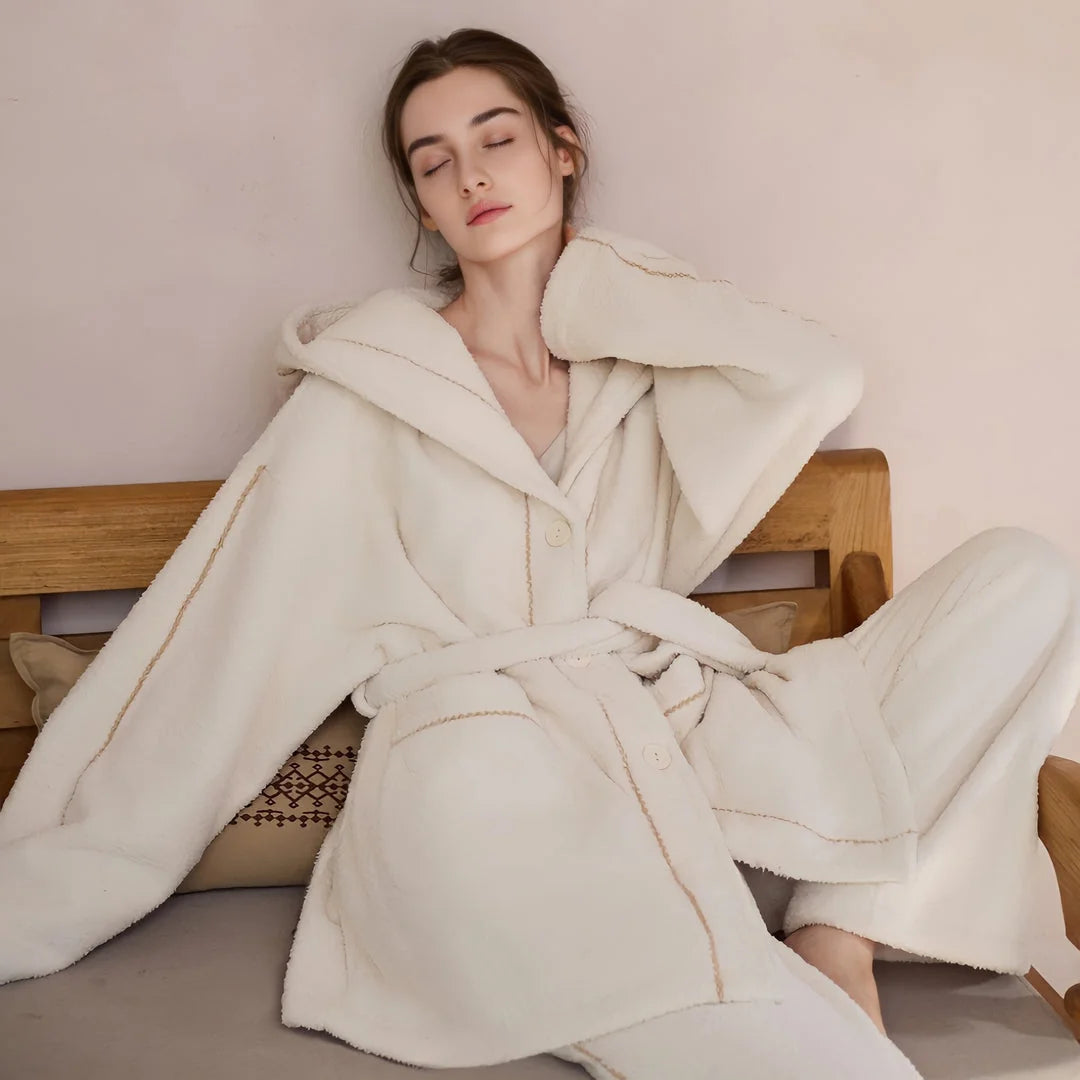 Model relaxing with eyes closed, showcasing the soft texture of the creamy white hooded fleece pajama top - RoomDen.