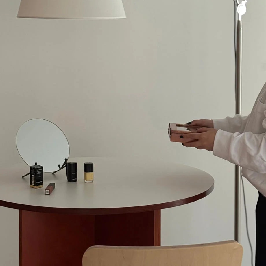 A person holding a closed walnut brown wood jewelry box in a bright, minimalist room. - RoomDen