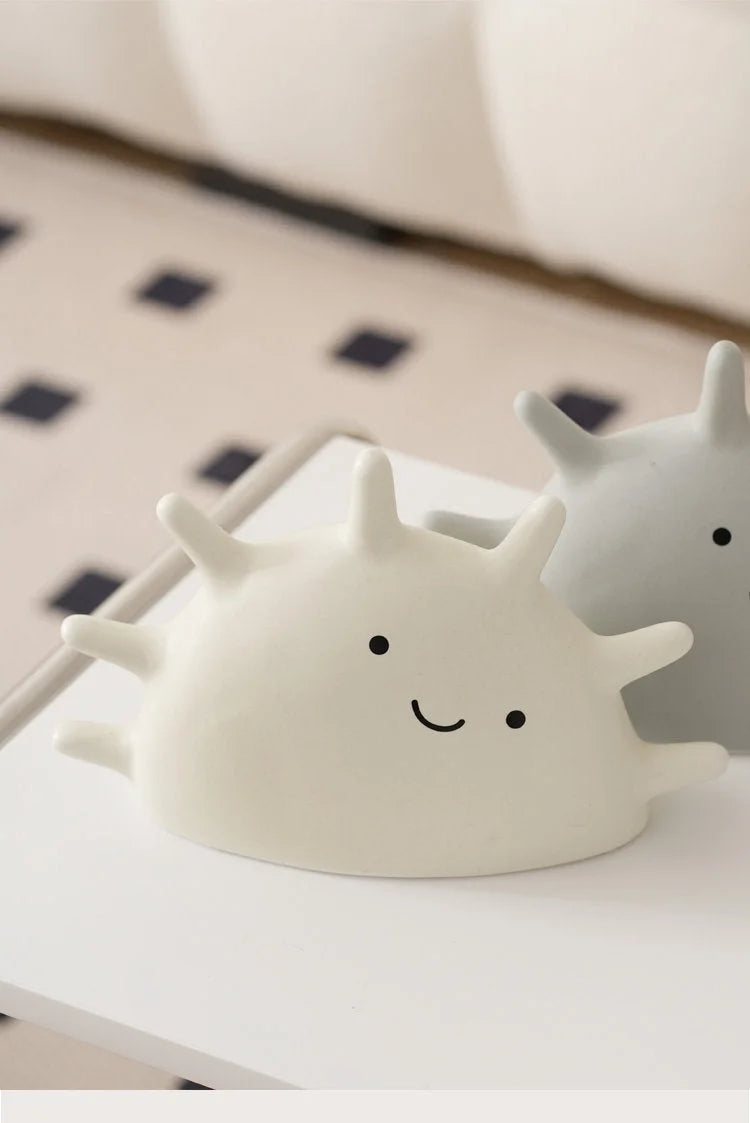 A white and a grey smiling sun jewelry organizer on a white surface with a checkered background - RoomDen