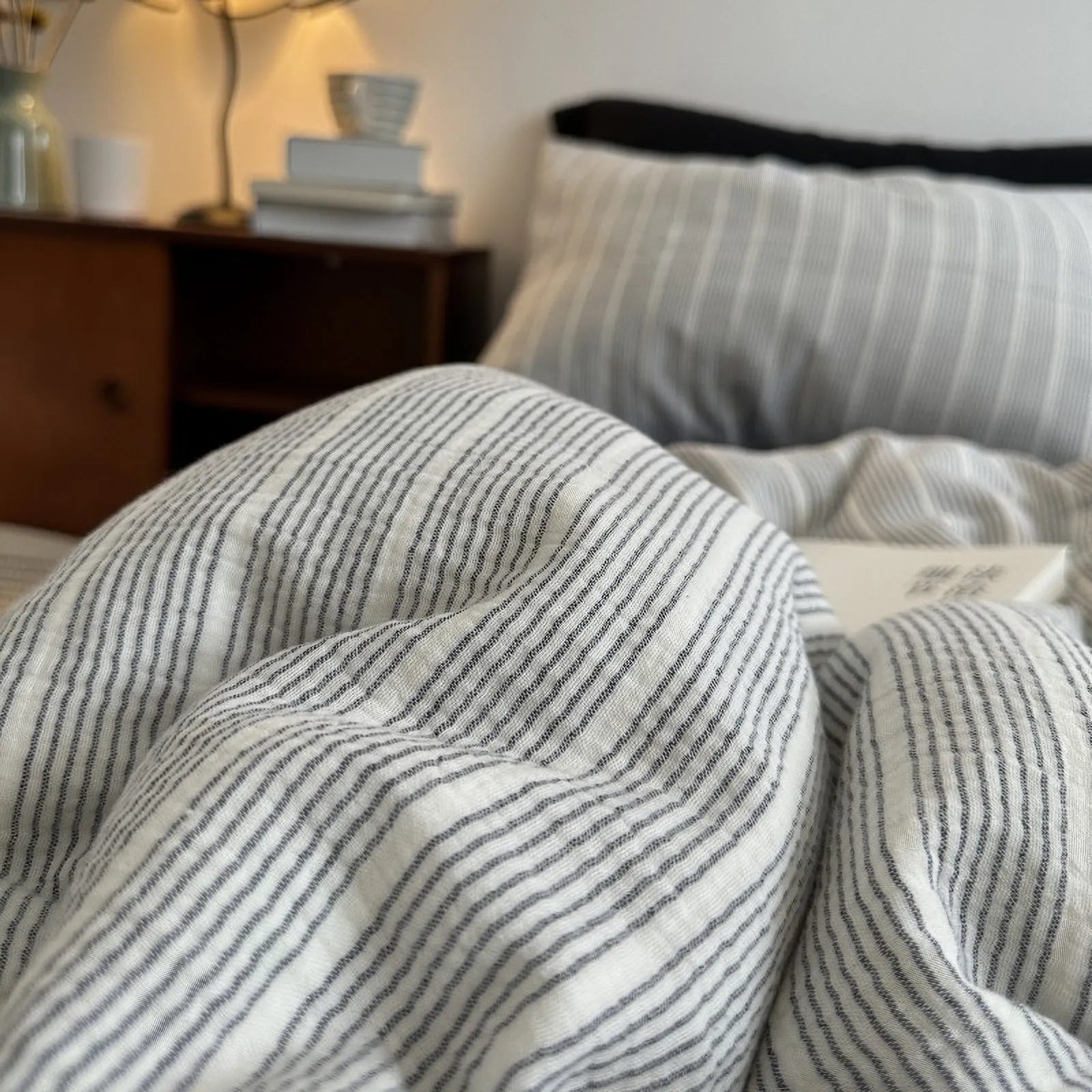 Cozy, warm-lit close-up of the grey pinstripe washed cotton duvet, creating a Hygge atmosphere.