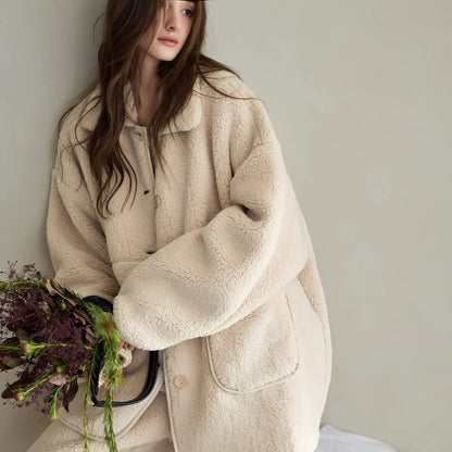 Model leaning against a wall holding a bouquet, wearing the Creamy Beige Fleece Pajama Set.