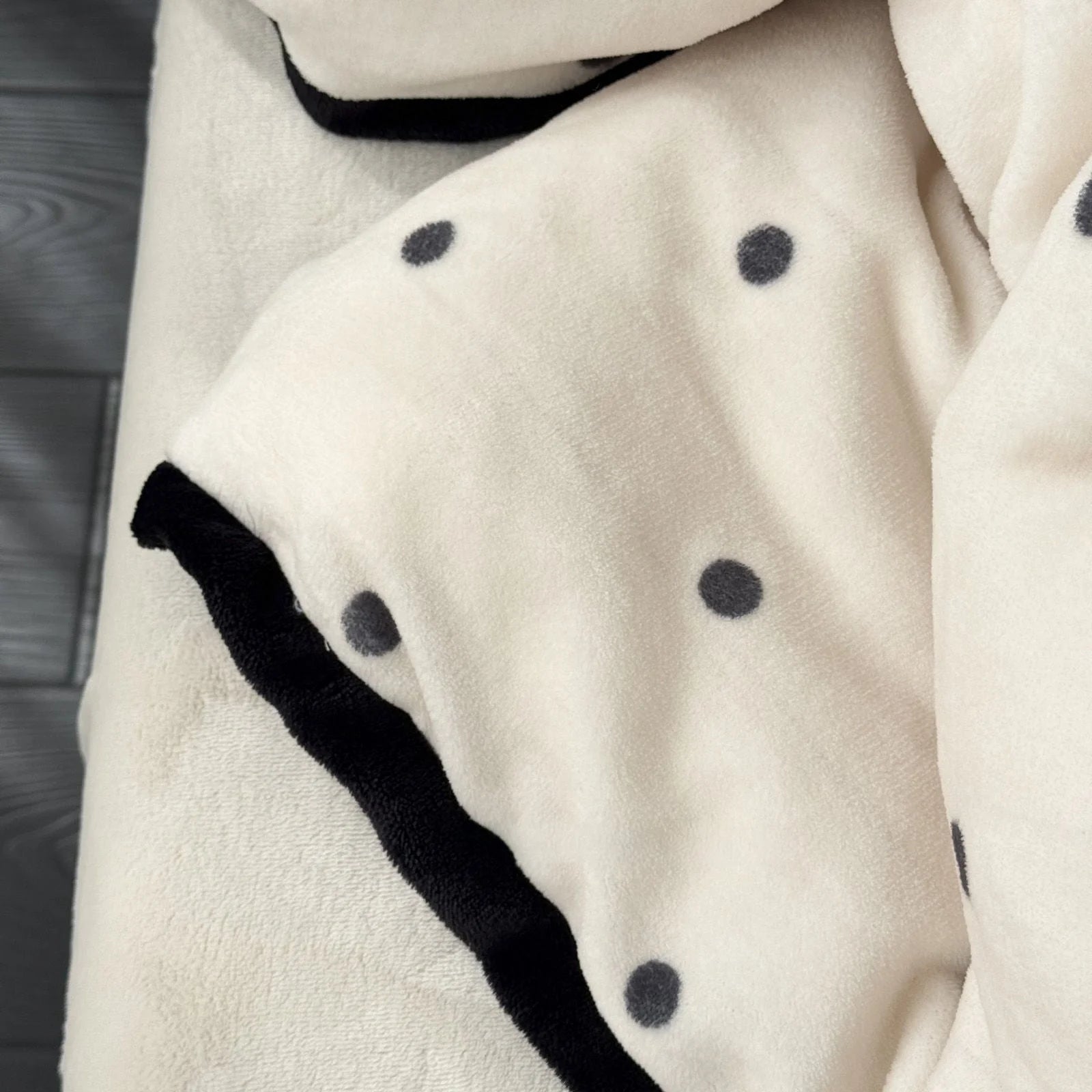Macro shot of the Creamy White Flannel Fleece fabric, showing the black polka dots and trim detail.