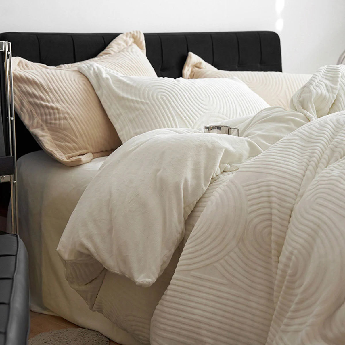 Side view showing the plush thickness of the cream white flannel fleece duvet cover and pillows on a black headboard.