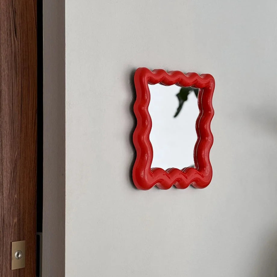 Closer view of the red wavy mirror, showcasing its bold color and unique frame shape - RoomDen