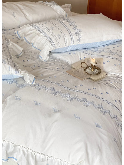 A full view of the bed made with the Ruffled Floral Vine Embroidered Cotton Bedding Set in blue.