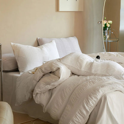 A messy, inviting view of the Classic White pintuck duvet cover, emphasizing its coziness.