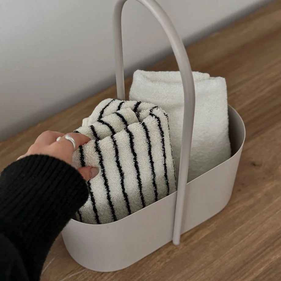 A hand reaching for the beige metal organizer caddy to demonstrate its portability. - RoomDen