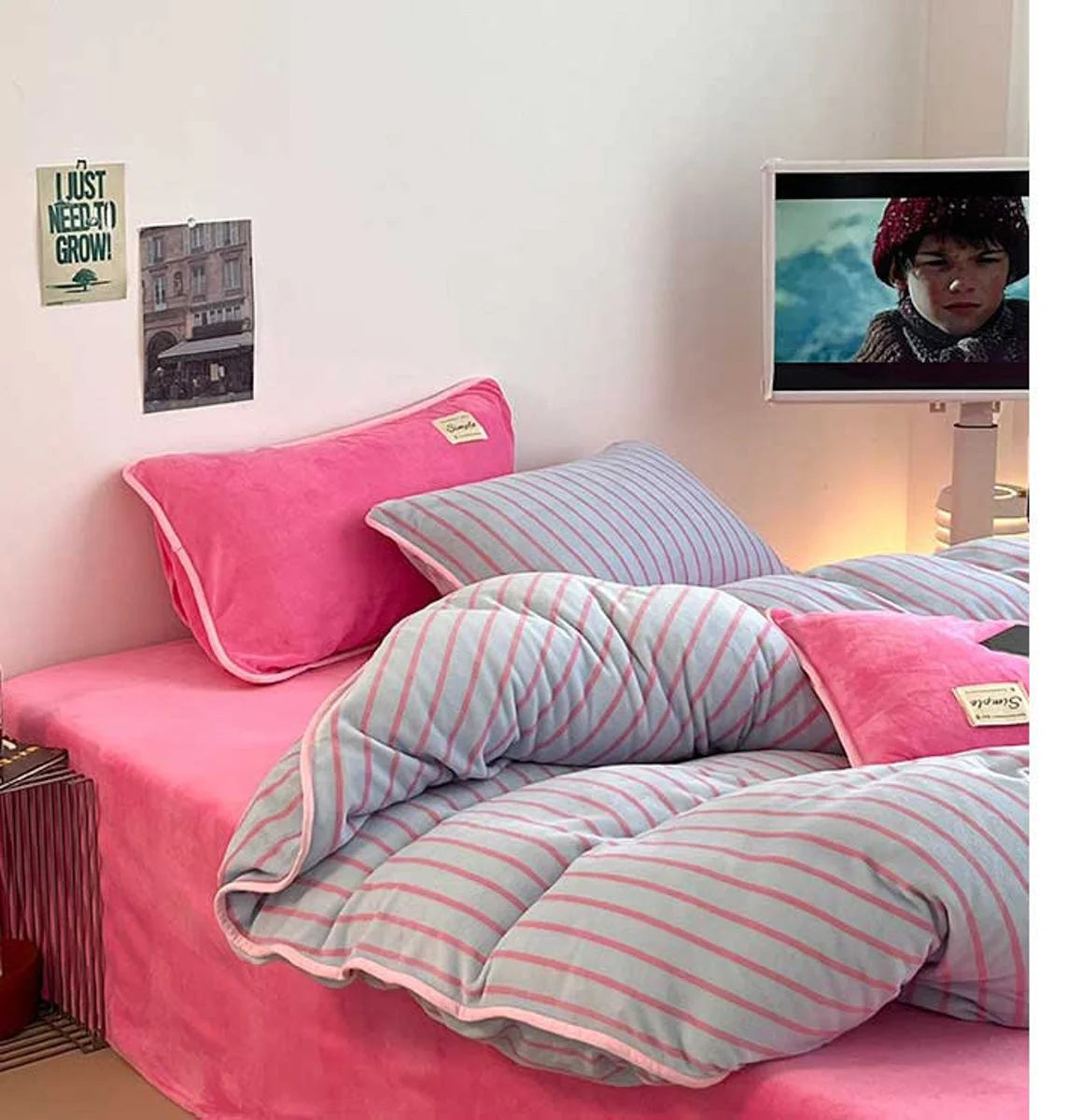 Side view of the Bubblegum Pink striped bedding set in a dorm room setting with a TV. - RoomDen