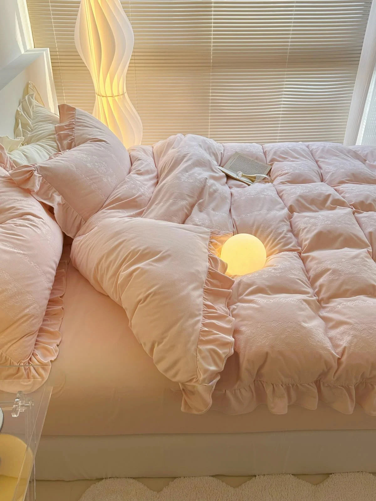 The Blush Pink Velvet Bedding Set in a cozy bedroom setting with a modern floor lamp. - RoomDen