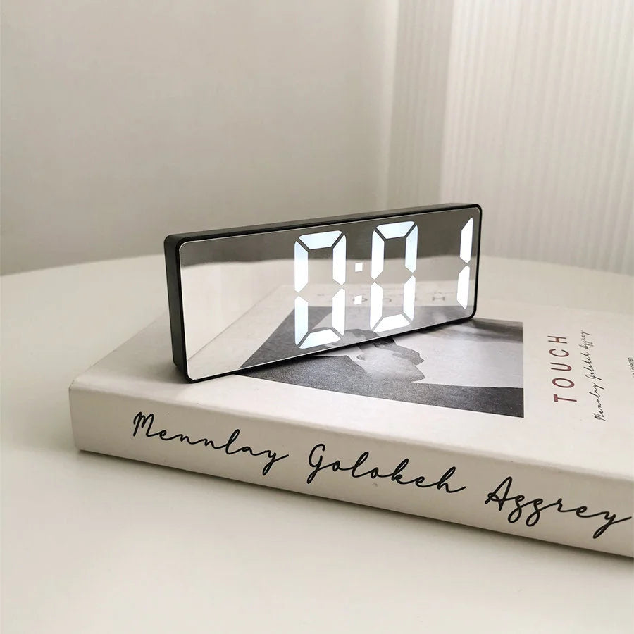 Close-up of the black Mirrored Acrylic LED Table Clock on a book, highlighting its sleek mirrored finish. - RoomDen