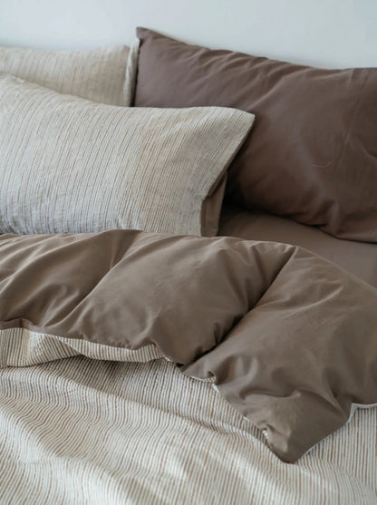 Close-up view highlighting the contrast between the pinstripe pillowcase and the solid brown pillowcase.