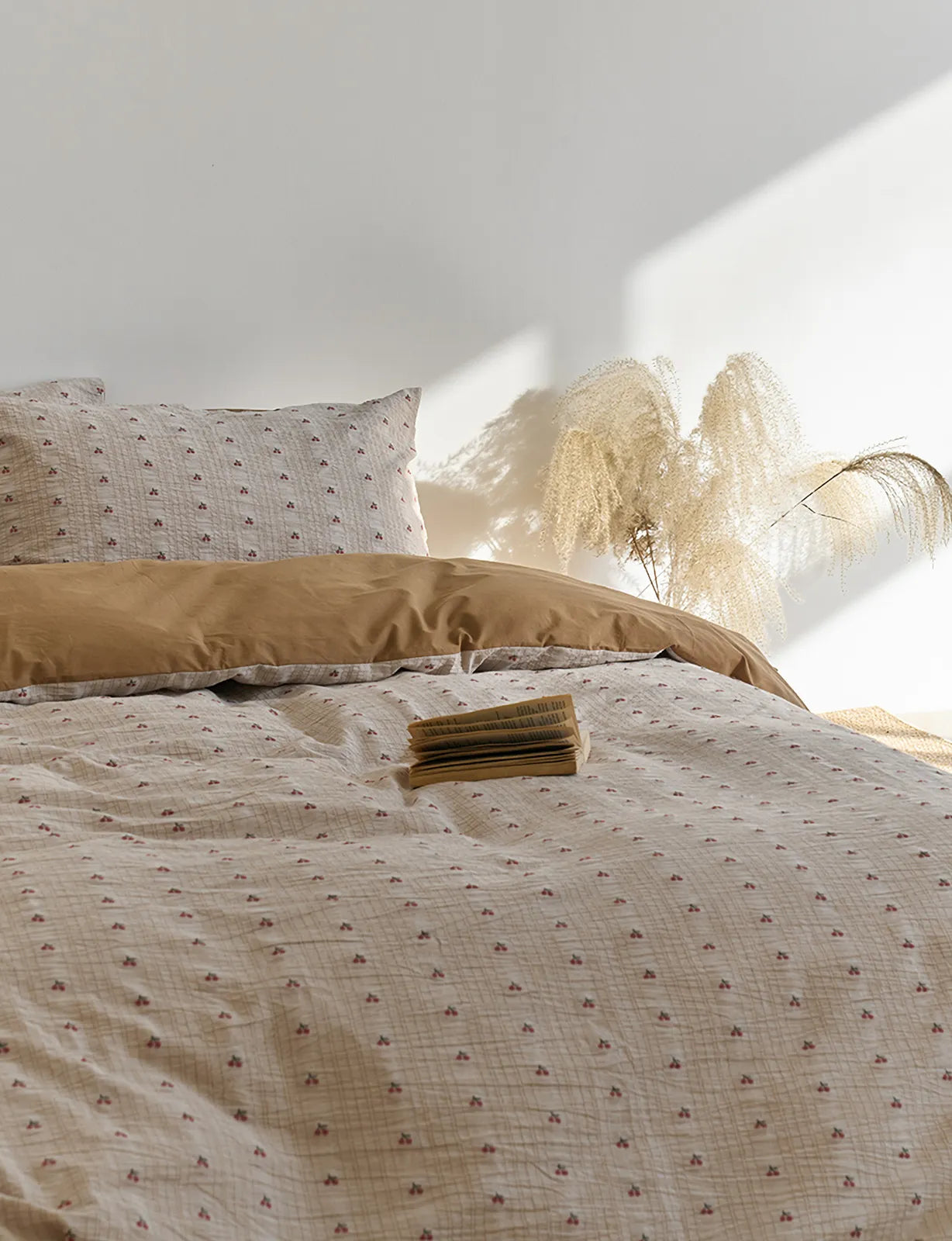 Ditsy Cherry Washed Cotton Bedding Set with an open book and pampas grass in the background, creating a serene vibe - RoomDen.
