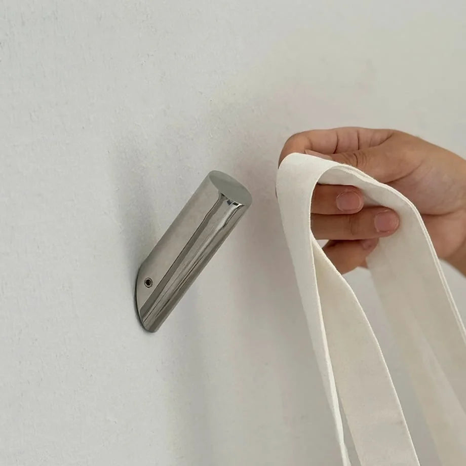 Close-up of the polished silver metal wall hook being used to hang a white canvas tote bag. - RoomDen