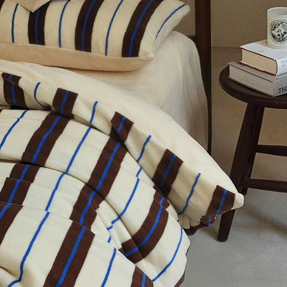Detail shot of the corner of the cream and brown striped velvet duvet cover - RoomDen.