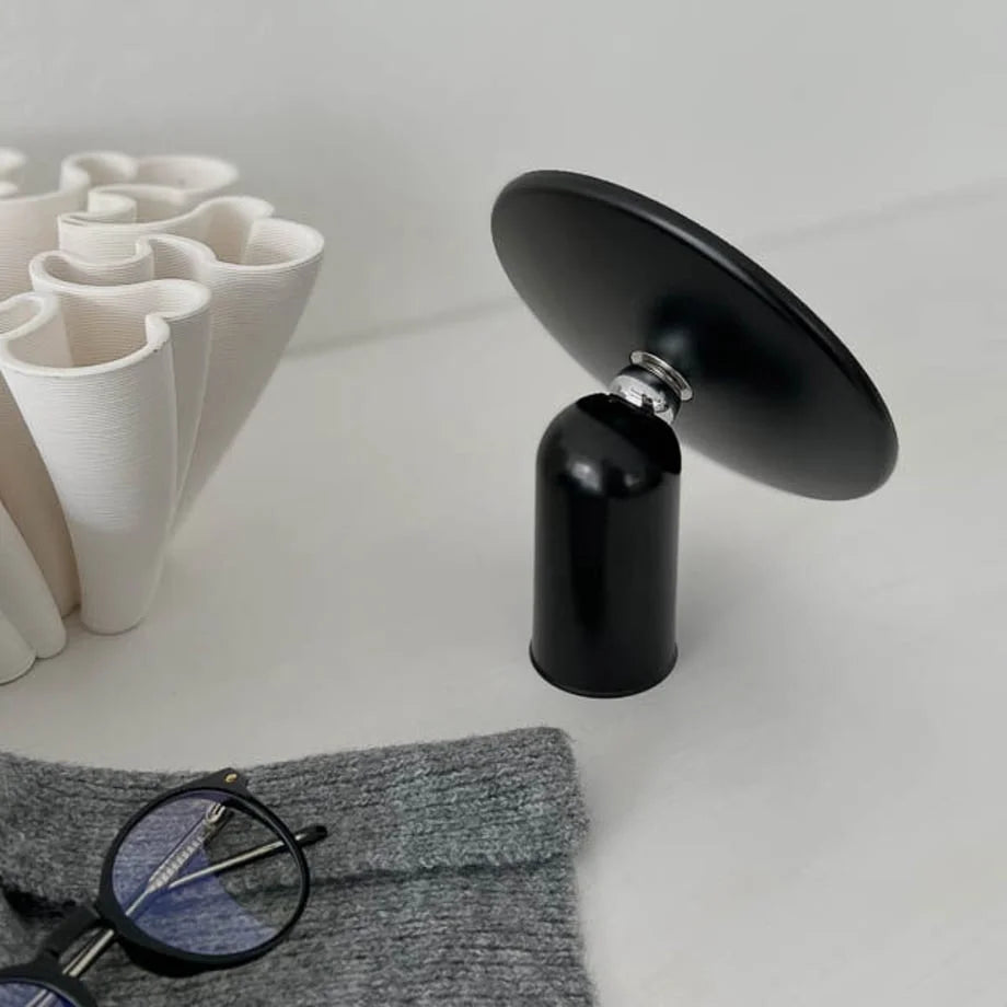 Angled view of the black minimalist vanity mirror tilted upwards, showing the chrome joint.