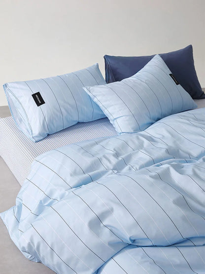Lifestyle shot of the Sky Blue Pinstripe Washed Cotton Bedding Set, layered with a solid pillow for a styled look - RoomDen.