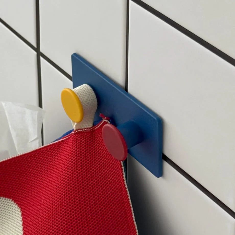 Side view of the Blue Colorblock Decorative Hook on a tiled wall, demonstrating its strong adhesive hold on a towel - RoomDen.