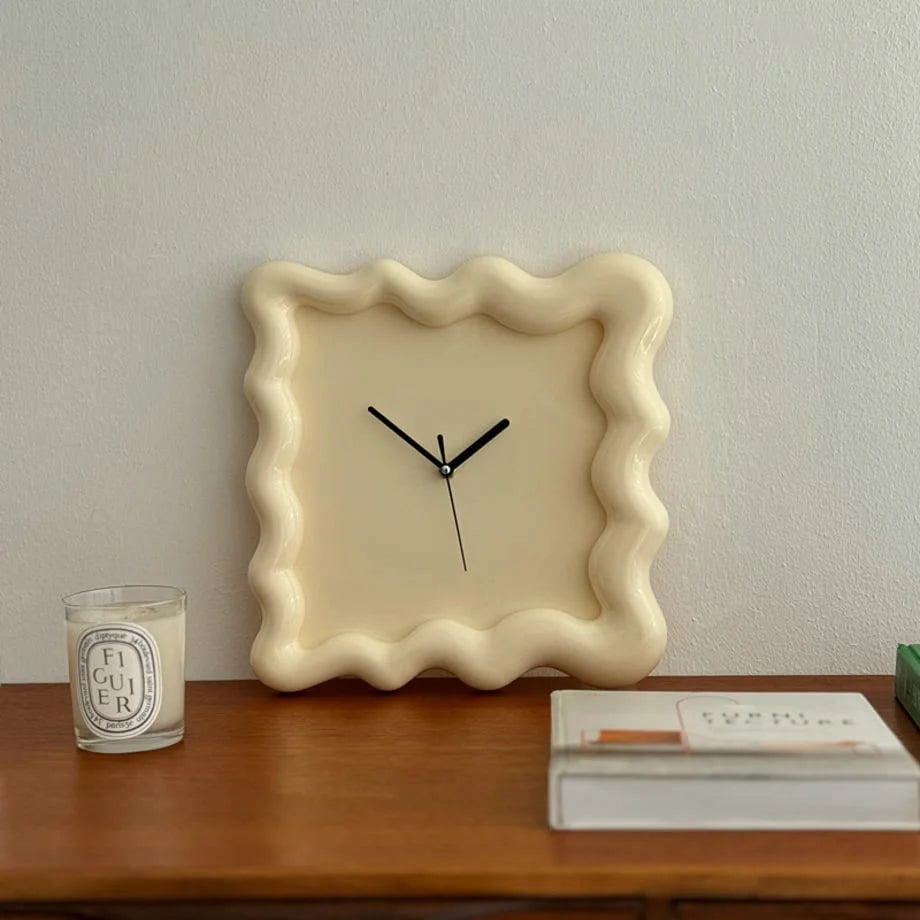 Direct front view of the cream Wavy Squiggle Frame Clock on a wooden surface. - RoomDen