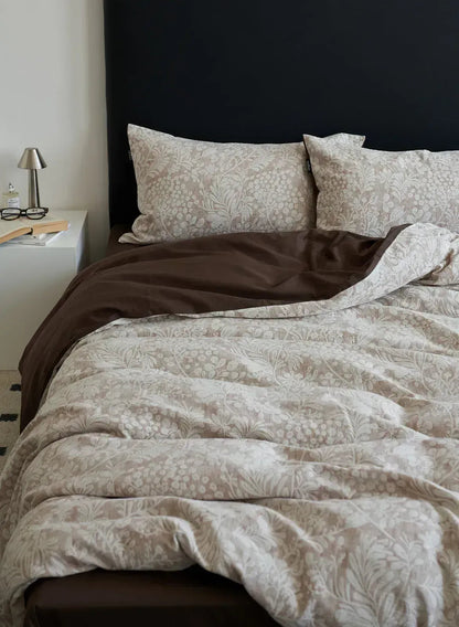 The Jacquard Botanical Washed Cotton Bedding Set in taupe brown, styled on a bed with a dark headboard, showing the dark brown reversible side - RoomDen.