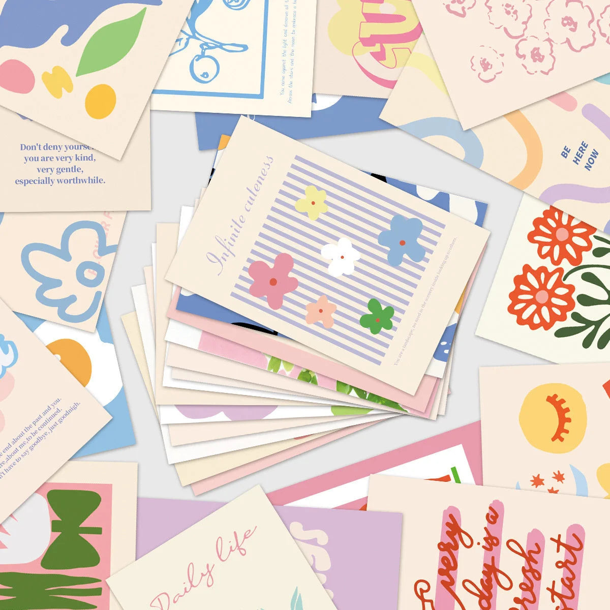A scattered pile of colorful cards from the Vibrant Danish Pastel Wall Collage Kit, showing various floral and abstract designs. - RoomDen