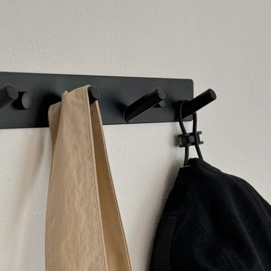 Close-up of the black metal wall hooks showing the angled pegs and matte finish - RoomDen.