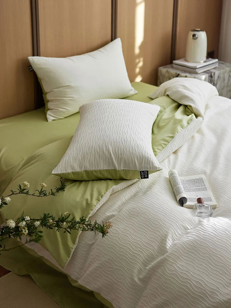 Close-up of the Cream White Wavy Textured pillow sham on a Matcha Green sheet. - RoomDen