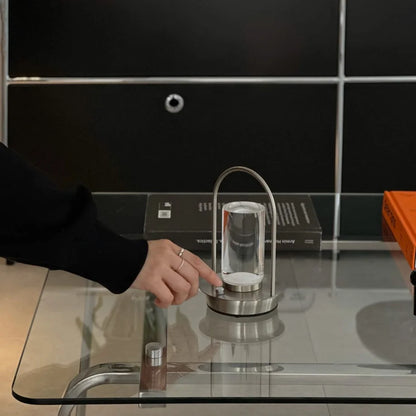 Close-up of a finger pressing the button on the silver metal portable lamp. - RoomDen