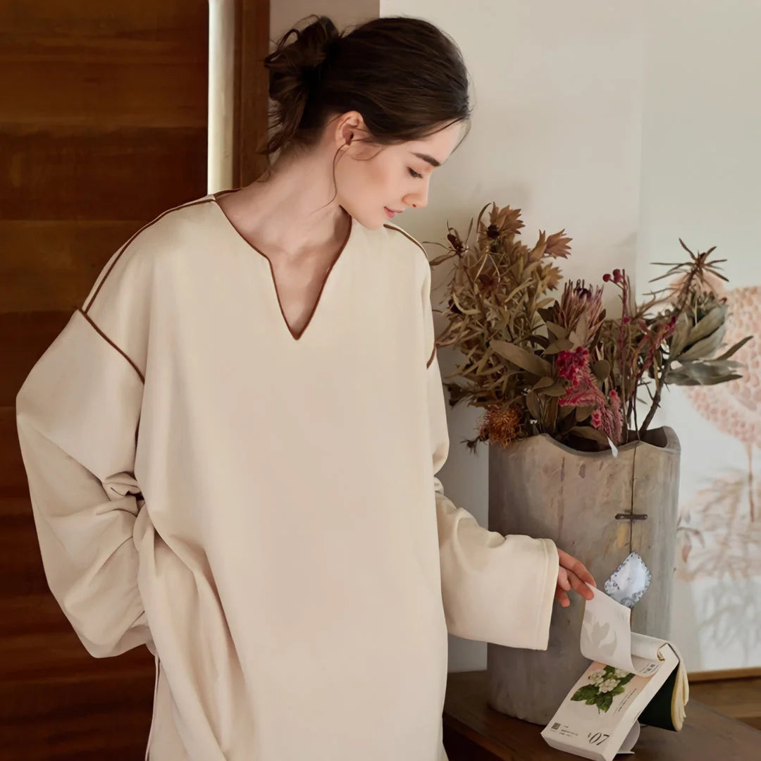 Model in the creamy beige plush pajama set looking at a small calendar on a wooden console. - RoomDen