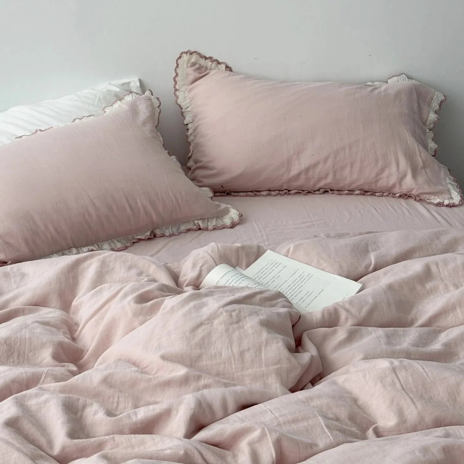 Dusty rose lace ruffle bedding set with an open book, creating a soft and romantic bedroom scene.