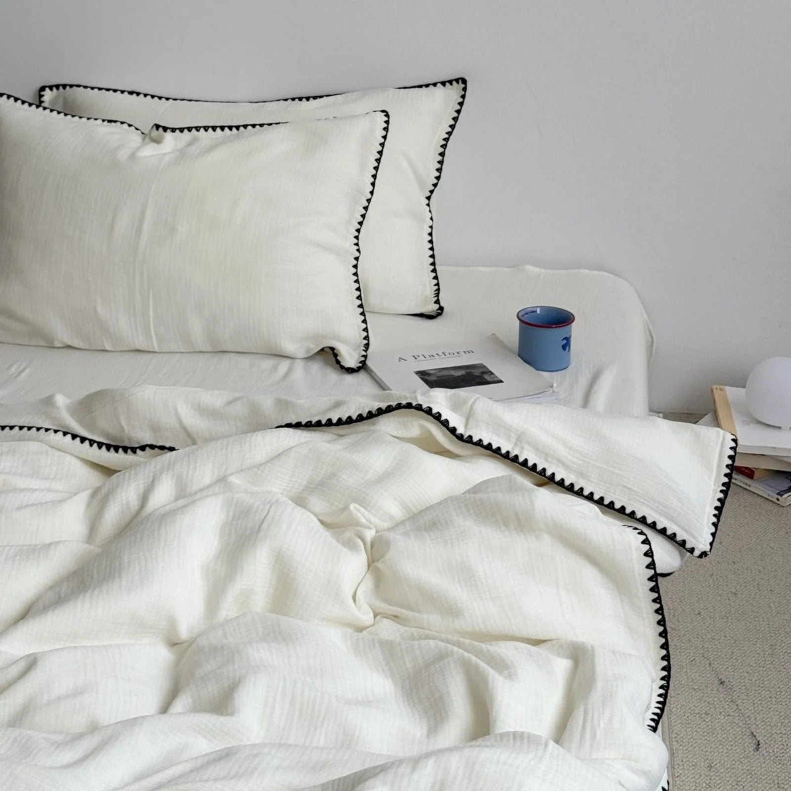 Lifestyle image of the cream white and black embroidered bedding set, showing its cozy and minimalist vibe.