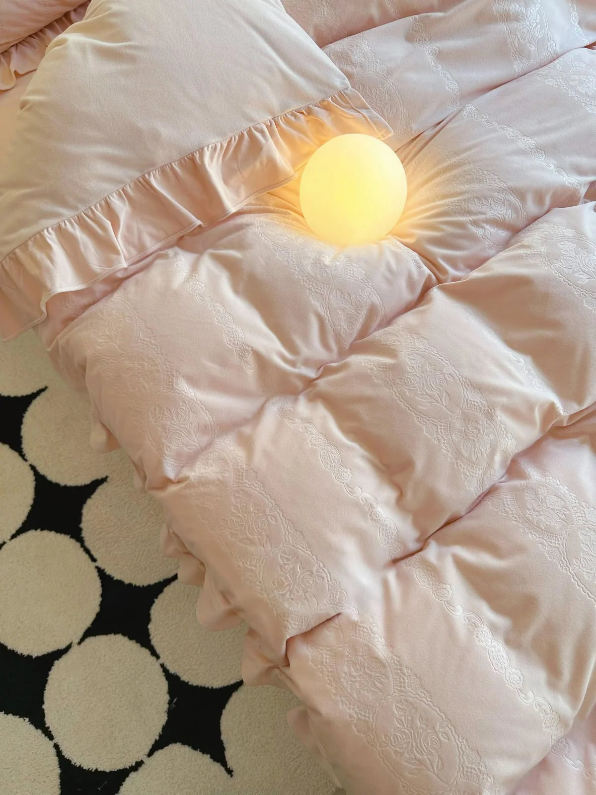 Top-down detail of the plush comforter and ruffled pillowcase in Blush Pink. - RoomDen