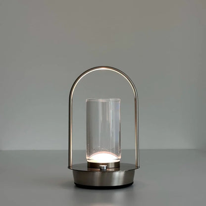 The Minimalist Arch Metal Portable Table Lamp turned on with a natural, soft white light. - RoomDen