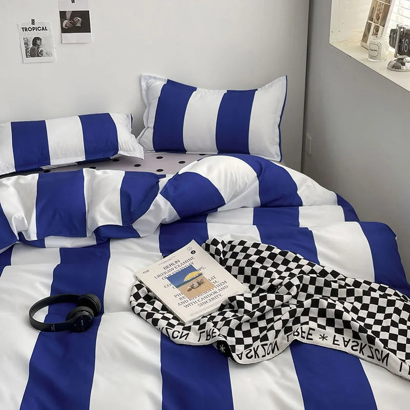 Close-up view of the Blue & White Striped Bedding Set with headphones and a checkered throw blanket - RoomDen